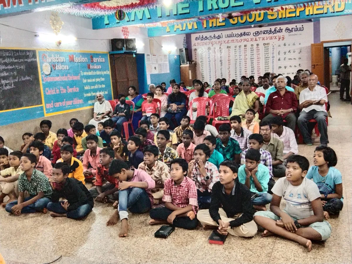 A large group of people, many of them children, seated in a hall at the home on 9 July 2022