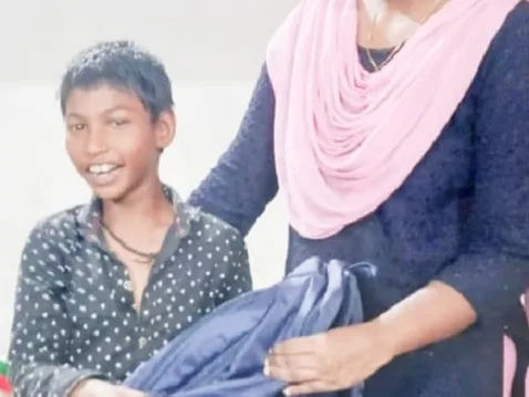 A smiling boy holding a bag, with a woman helping him