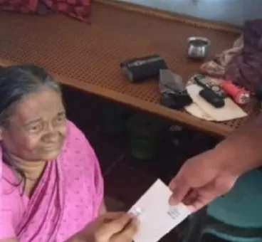An elderly woman smiling as she receives an envelope