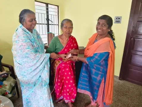Two elderly women being helped by a woman in a bright room