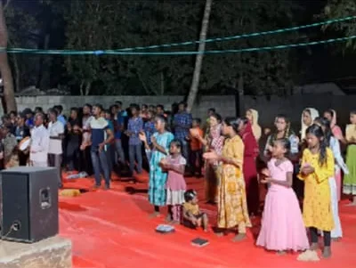 A crowd of children and adults gathered outdoors in the evening