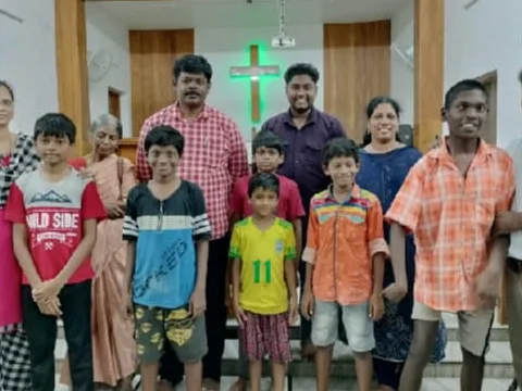Boys and adults standing together in front of a green cross