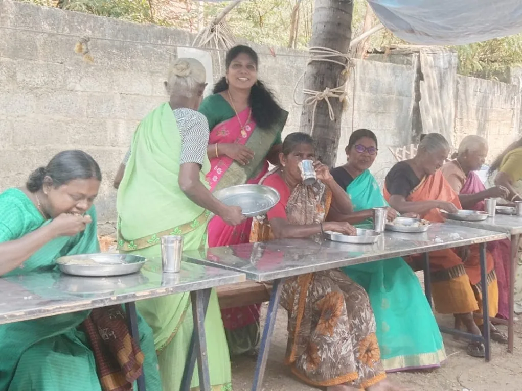 Elderly women eating at a long table outdoors
