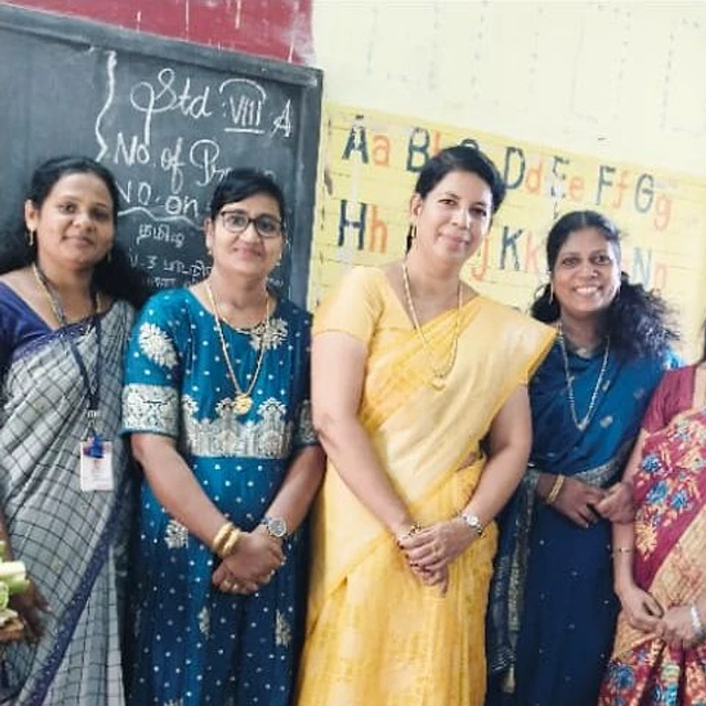 Women standing together in front of a classroom blackboard and a painted alphabet chart