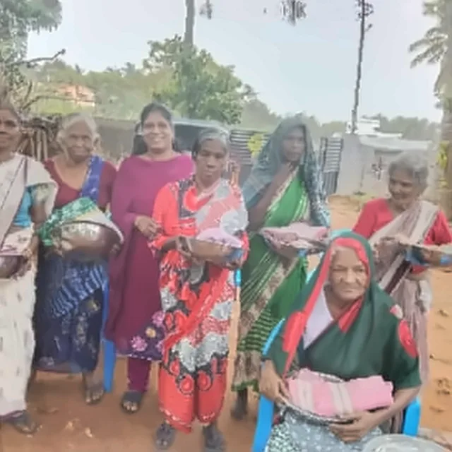 Women standing and sitting outdoors, holding steel plates and bowls