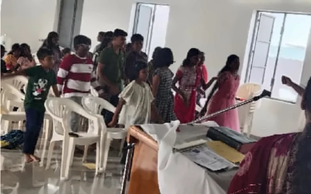 Children and young people standing together in a hall, with a table of books at the front